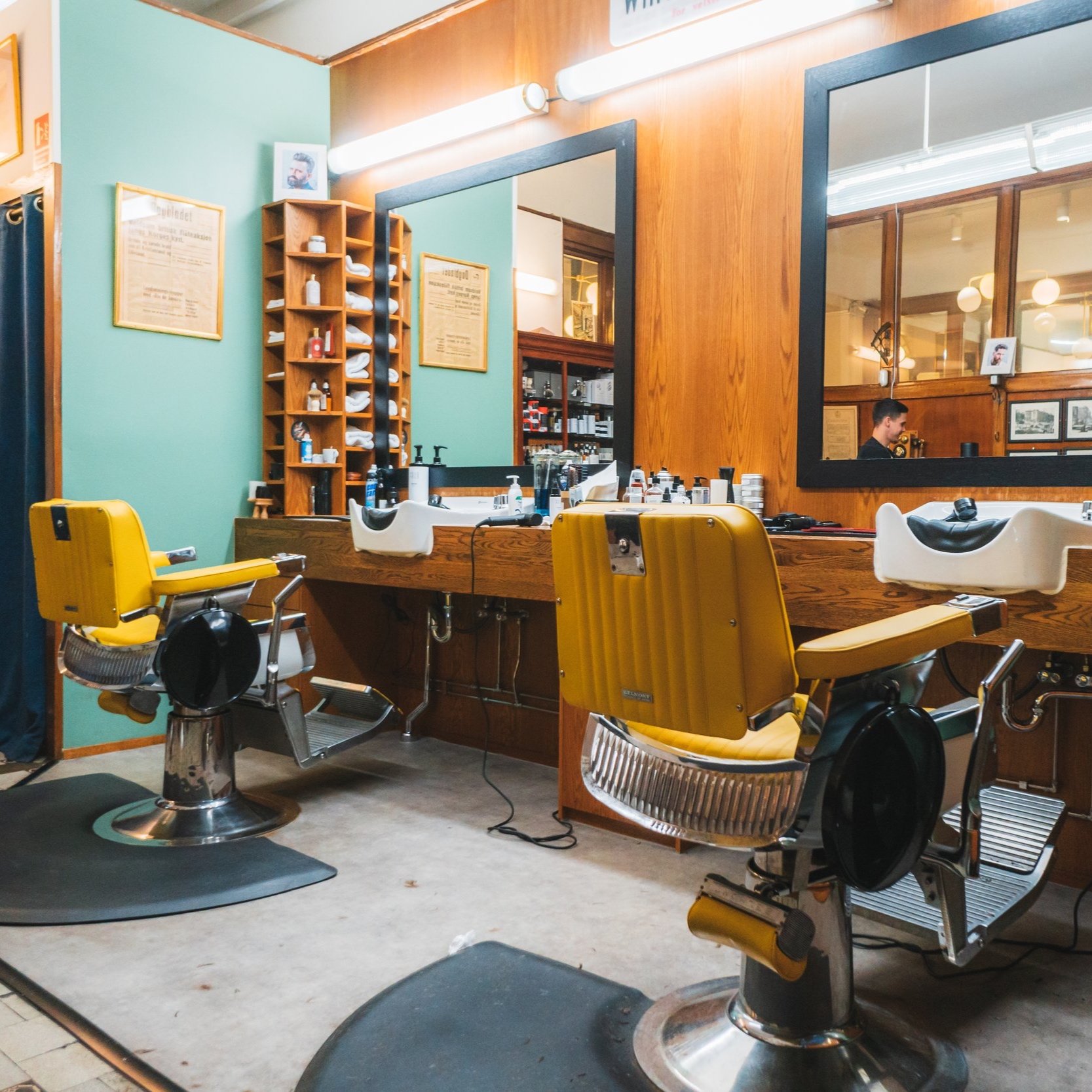 Interiør av klassisk barbersalong med to gule stoler og trepanel på veggene